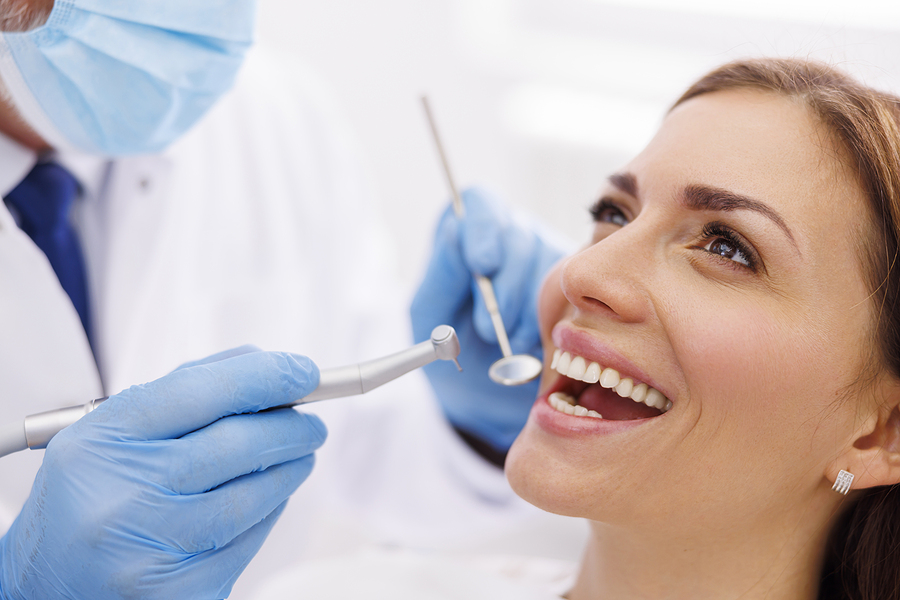 Dentist Fixing Patient's Tooth At Dental Clinic Using Dental Dri