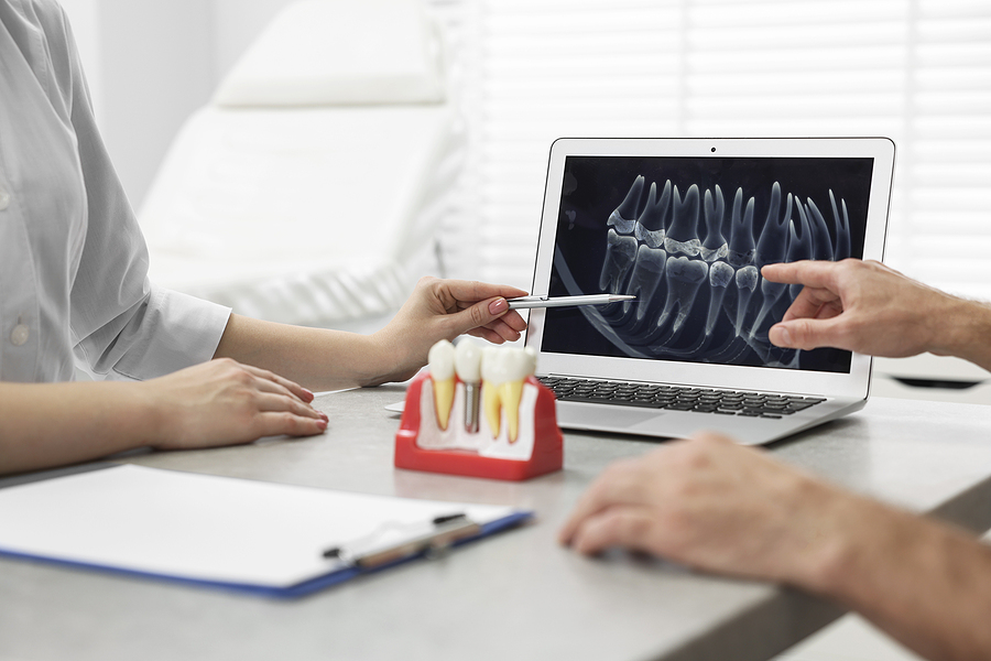Doctor Showing Patient X-ray Picture And Educational Model Of De